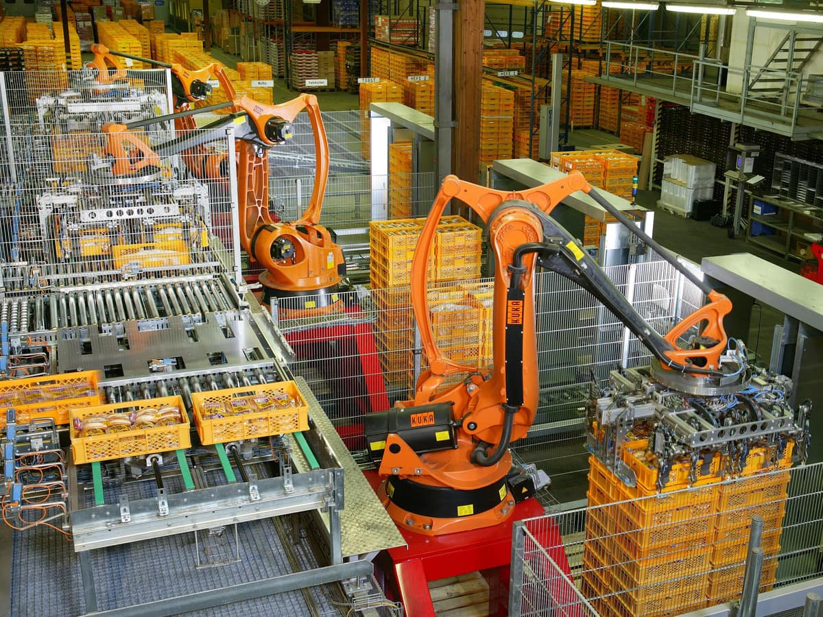 Orange industrial robots palletising crates on an automated factory line