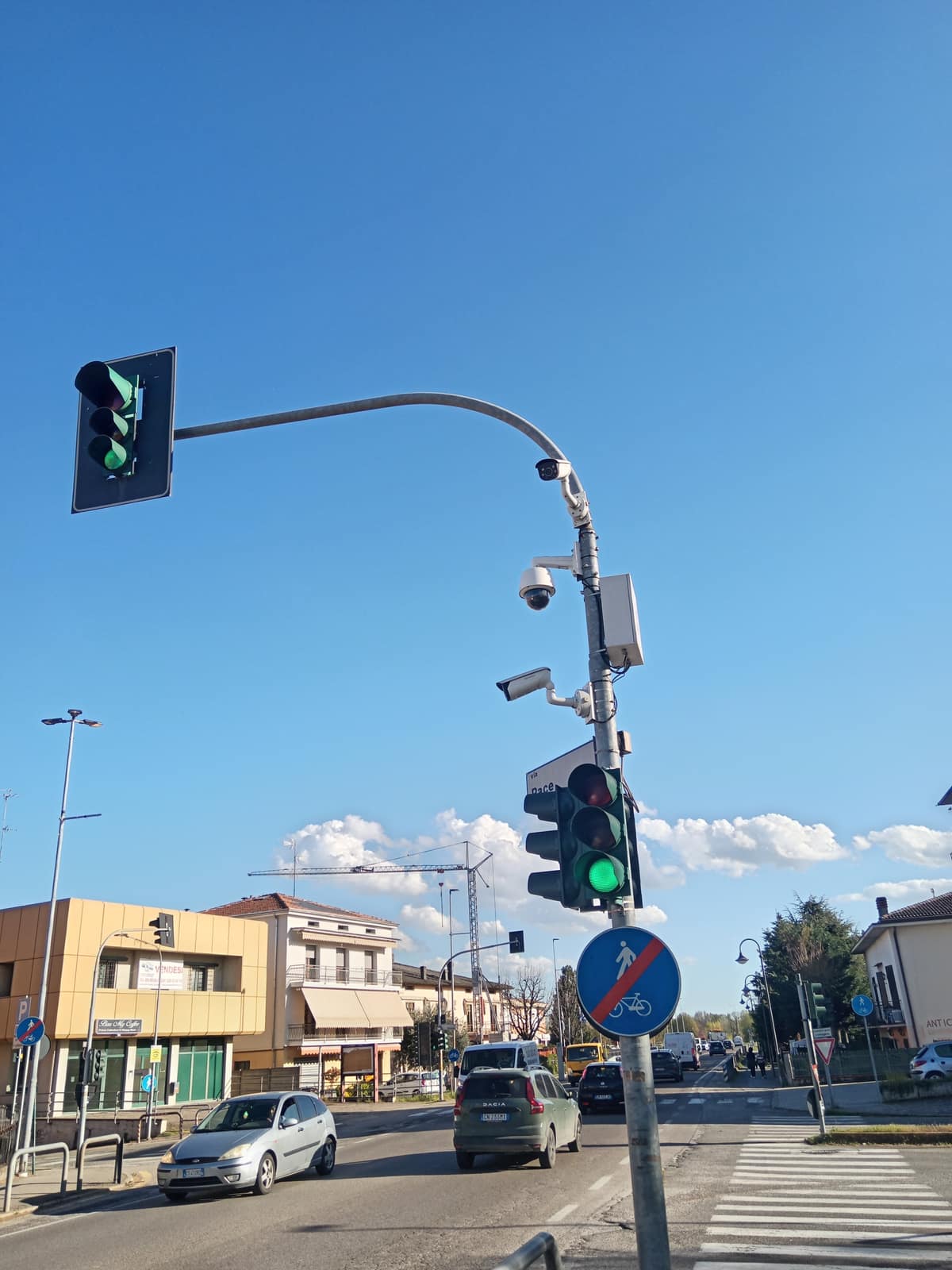 Traffic signal on a curved pole with CCTV cameras mounted beneath it